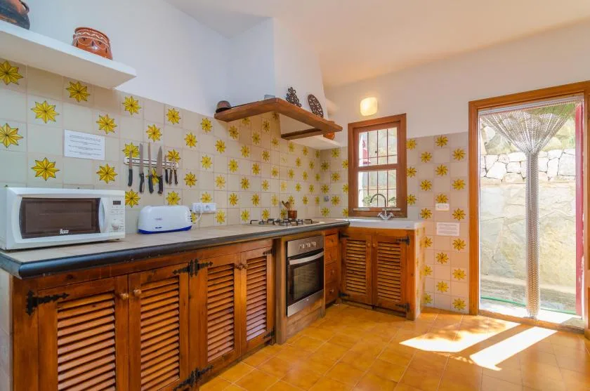 Una cocina luminosa con gabinetes de madera, paredes azulejadas y una encimera.