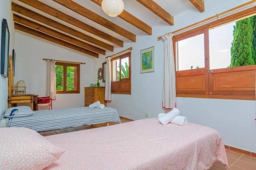 Un dormitorio con dos camas, vigas de madera en el techo y ventanas.