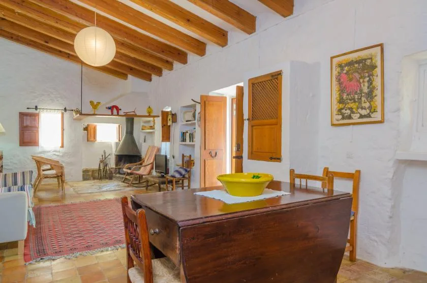 Comedor rústico con una gran mesa de madera y vigas de techo expuestas.