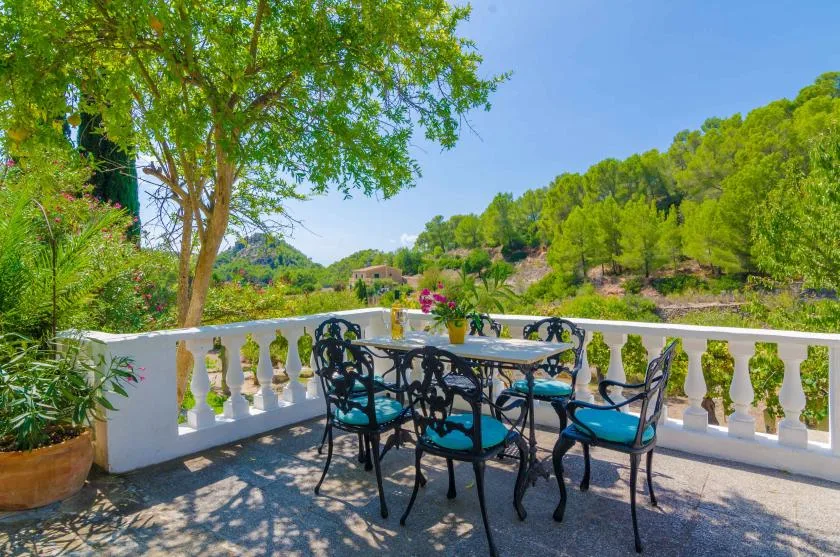 An outdoor terrace has a dining table and seating beside a white balustrade.