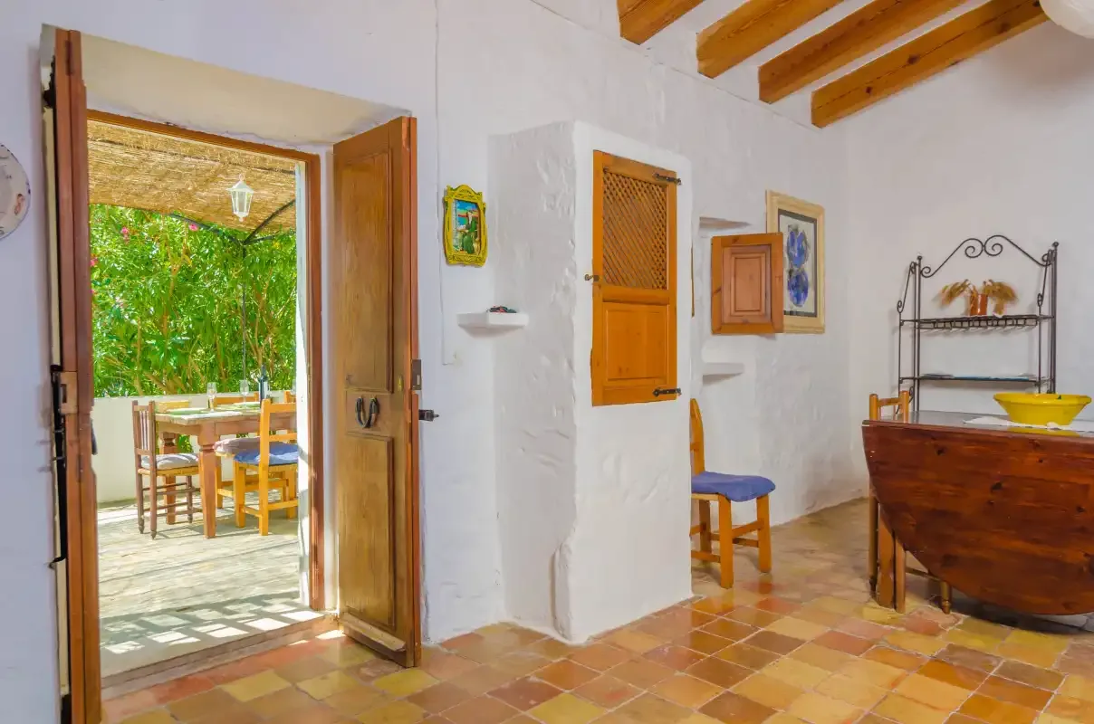 Un interior rústico con una puerta abierta que da a una zona de comedor exterior.