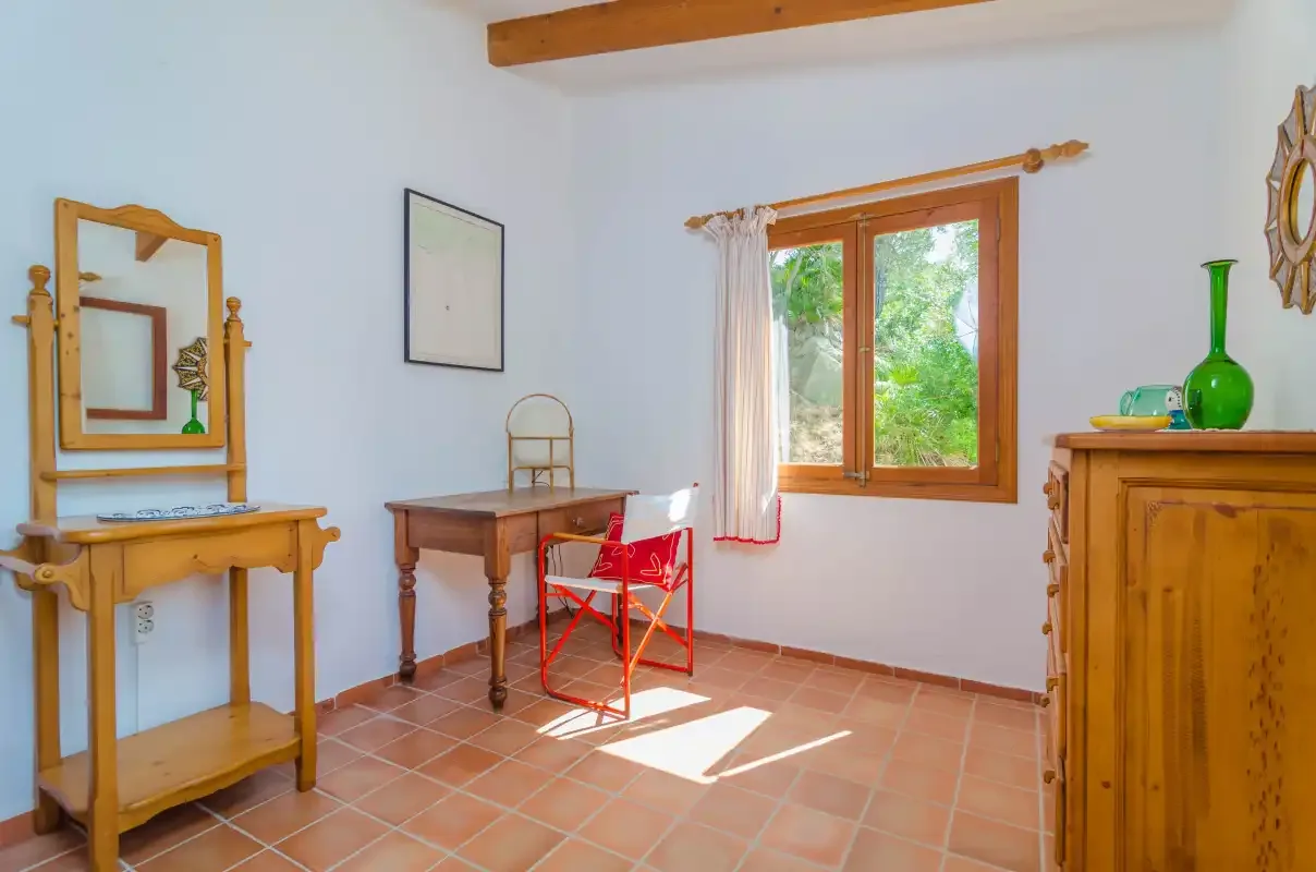 Una habitación luminosa con muebles de madera y una ventana que da a la vegetación.