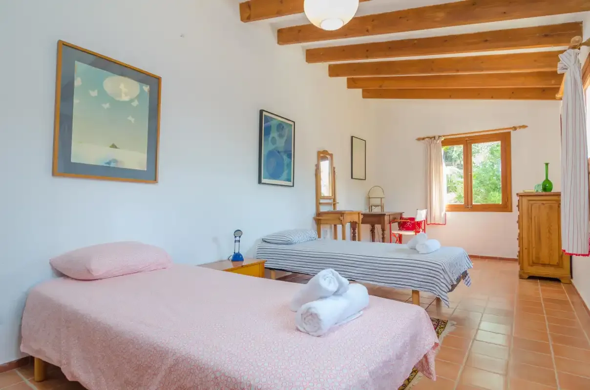Un dormitorio con dos camas, vigas de madera vistas y una ventana.