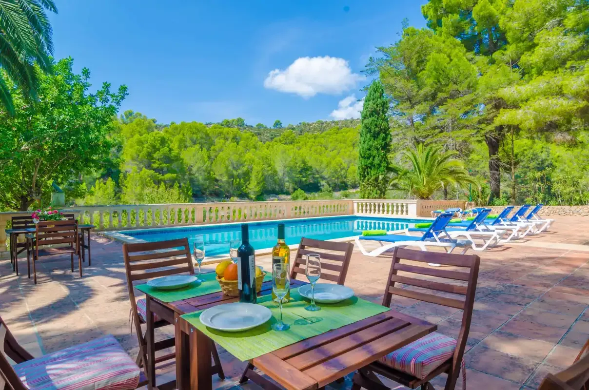 Una terraza con comedor junto a una piscina.
