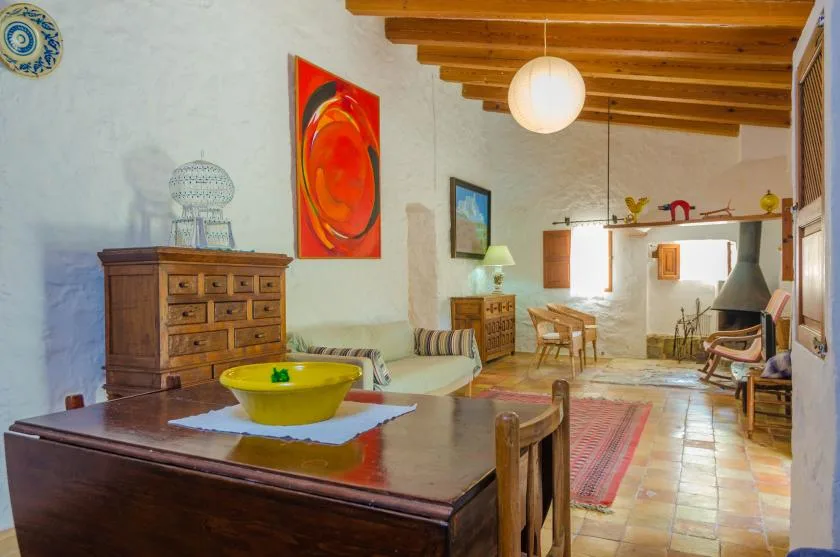 Una sala rústica con comedor, muebles de madera y obras de arte coloridas.