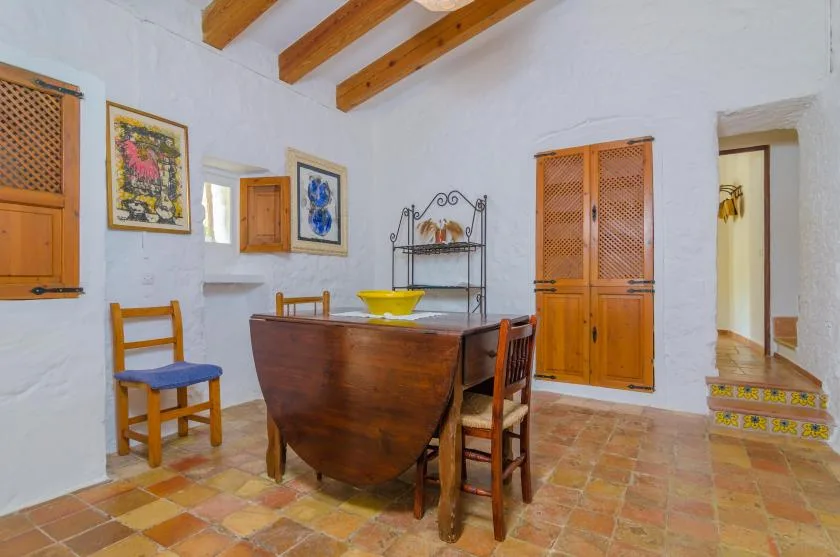 Un comedor con una mesa de madera, sillas y vigas de techo a la vista.
