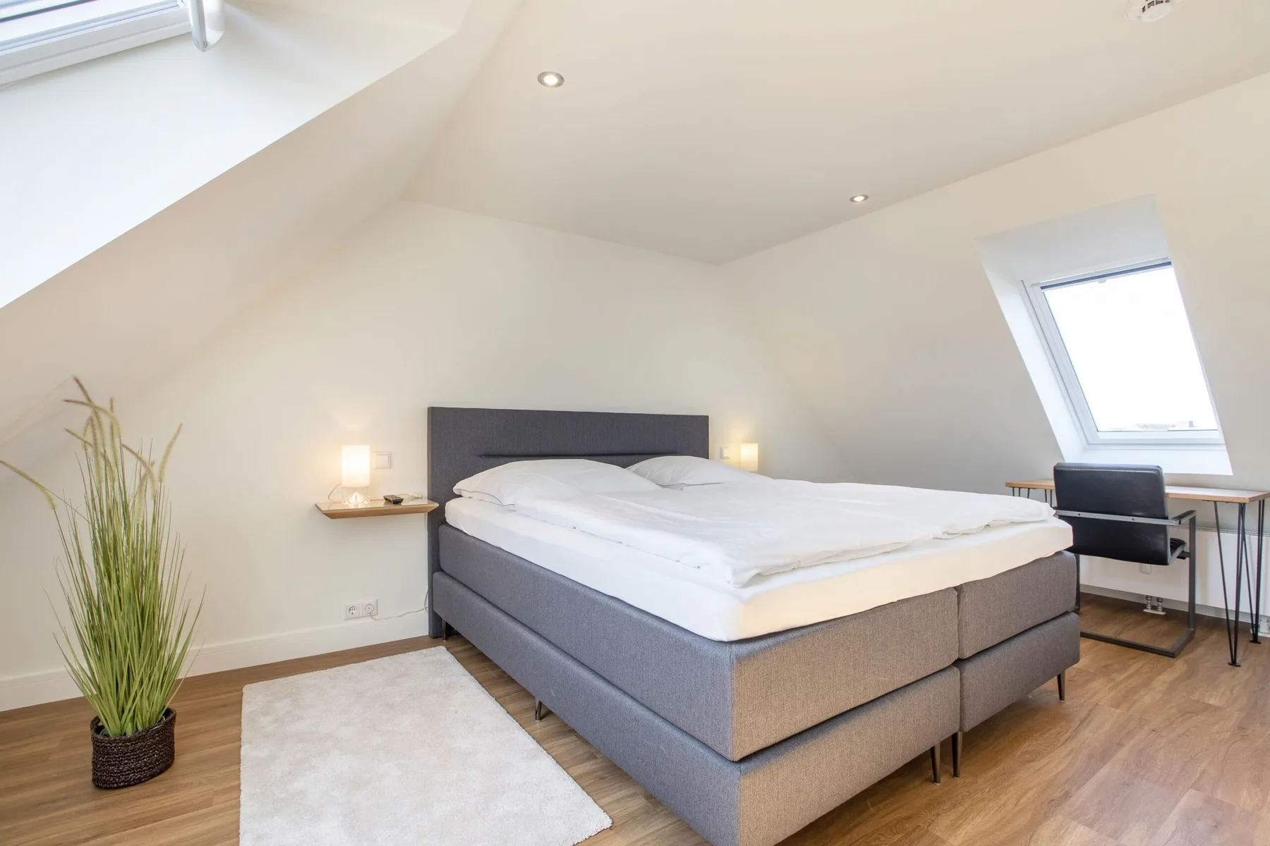 A bedroom with a large bed beneath a sloped ceiling.