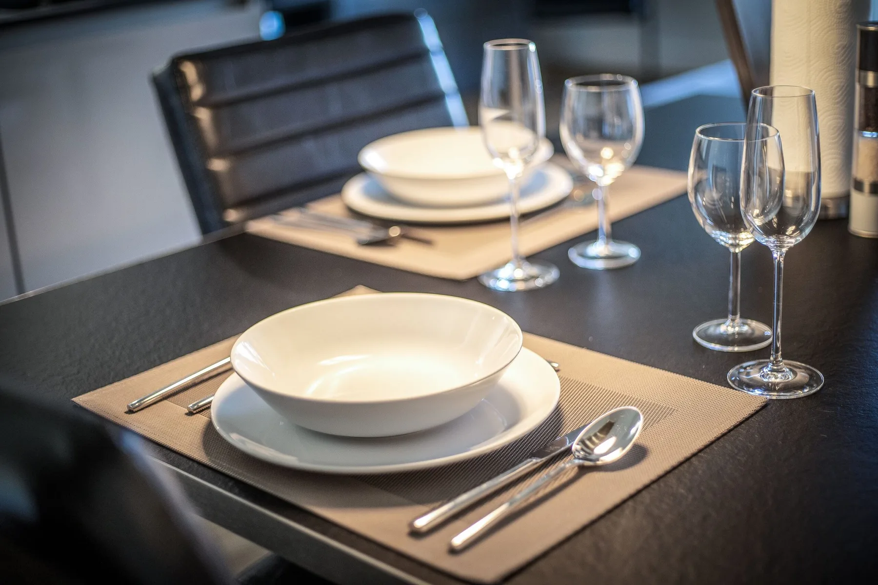 A dining table is set with plates, cutlery, and several wine glasses.