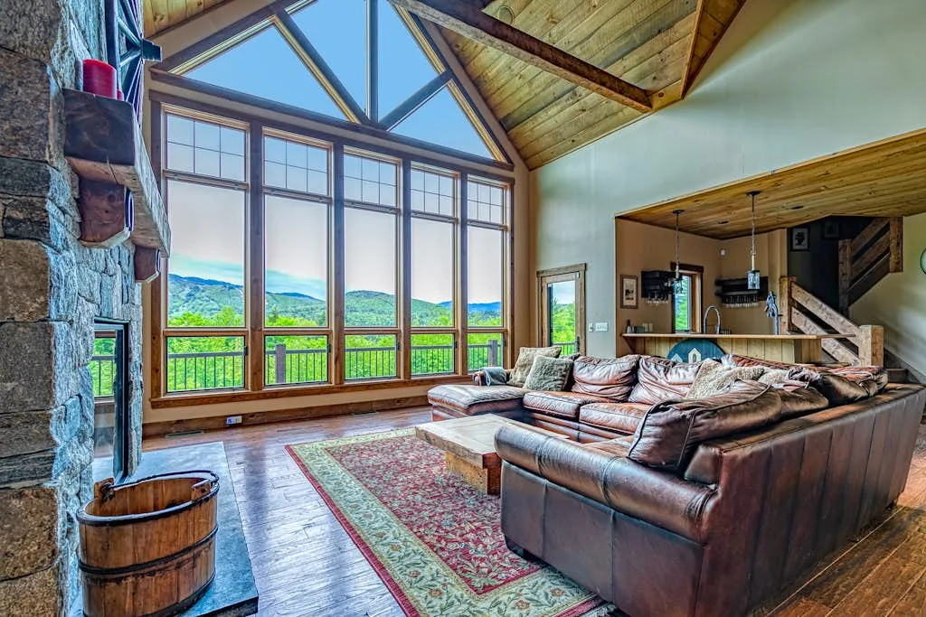A spacious living room has tall windows overlooking a green landscape.