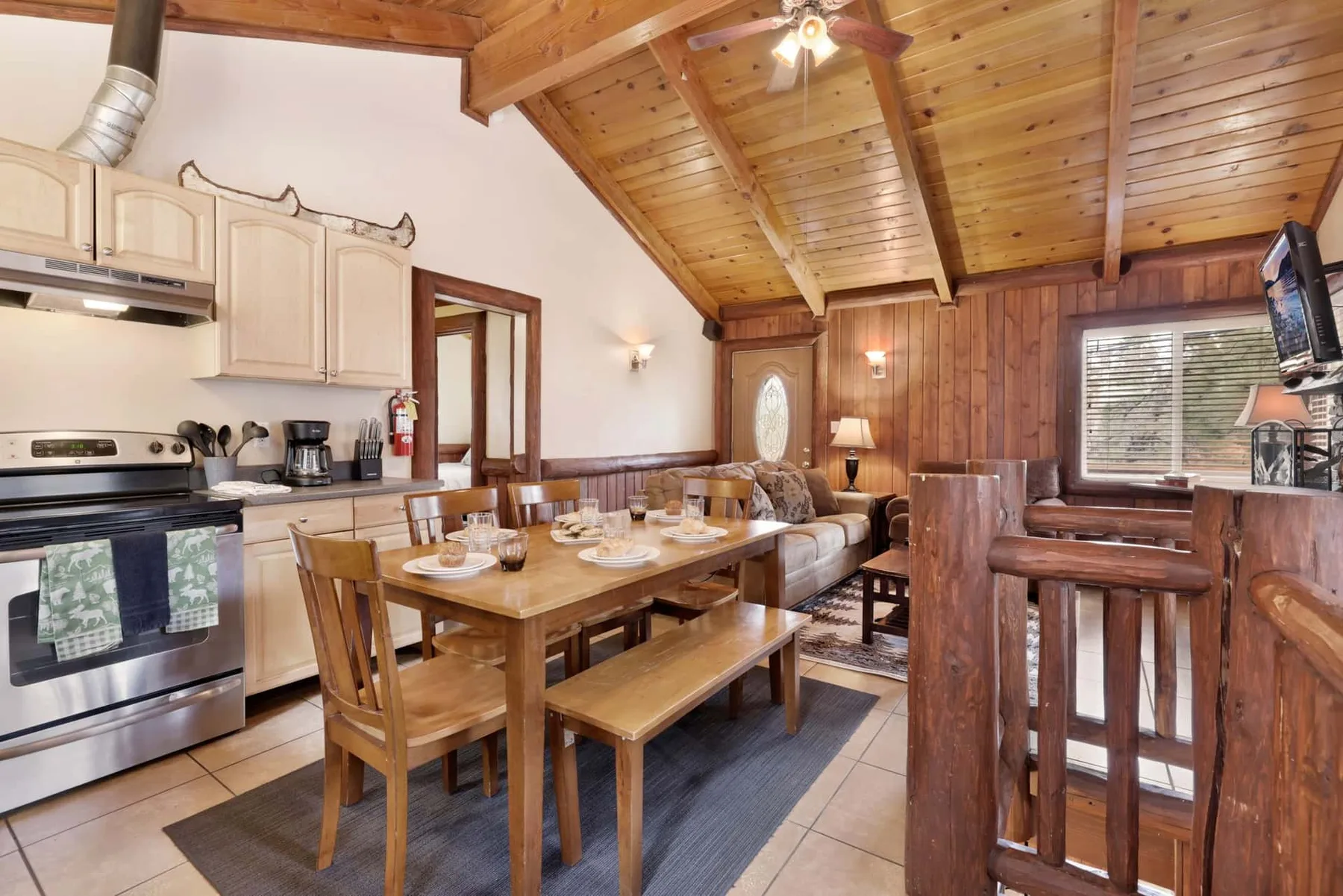 A wood-paneled dining area with a table, kitchen appliances, and a sloped ceiling.