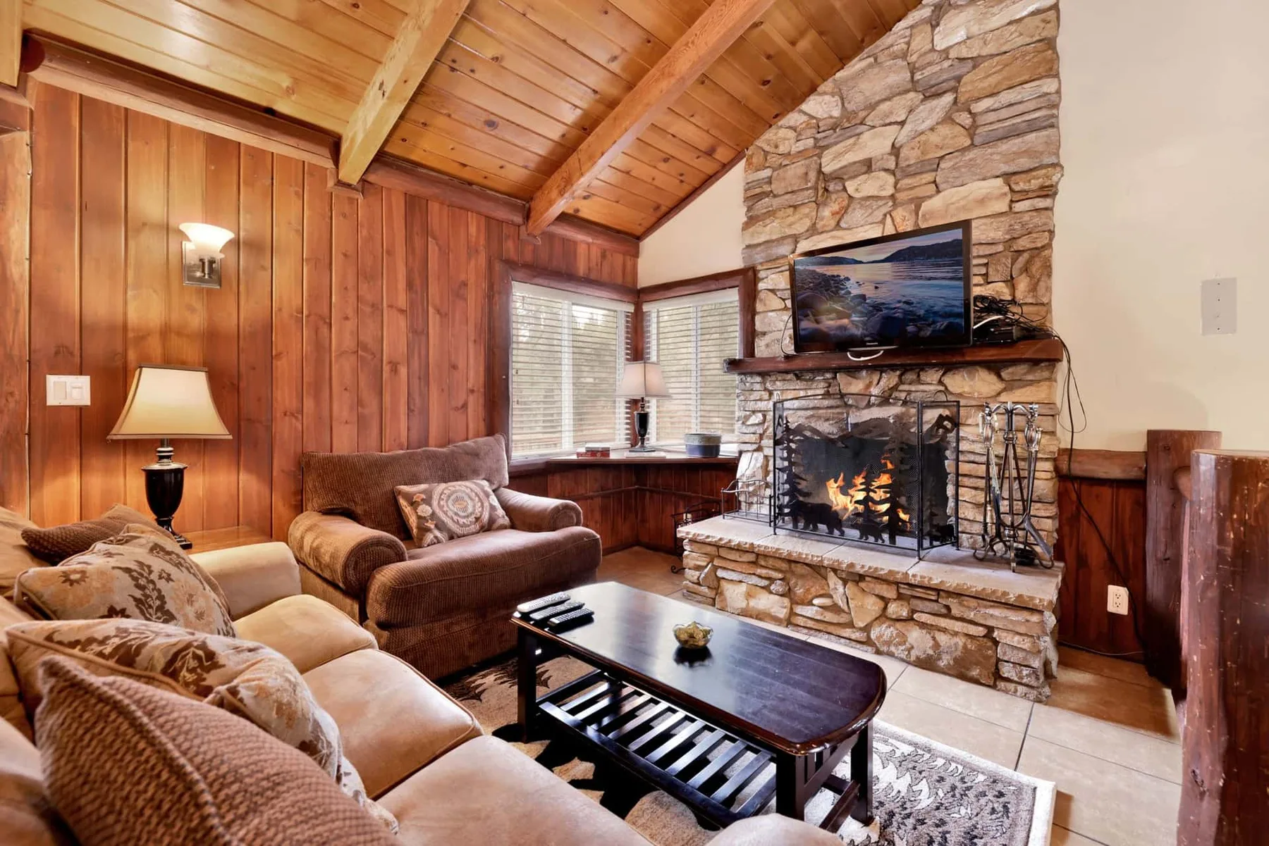 A wood-paneled living room with a stone fireplace and seating.