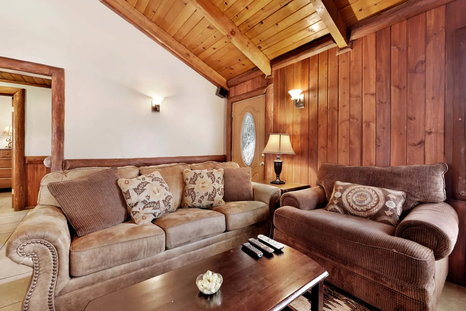 A living room with upholstered seating, a wooden ceiling, and a coffee table.