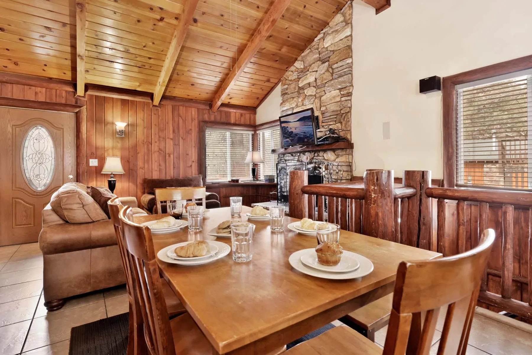 A dining area with a large wooden table and a stone fireplace.