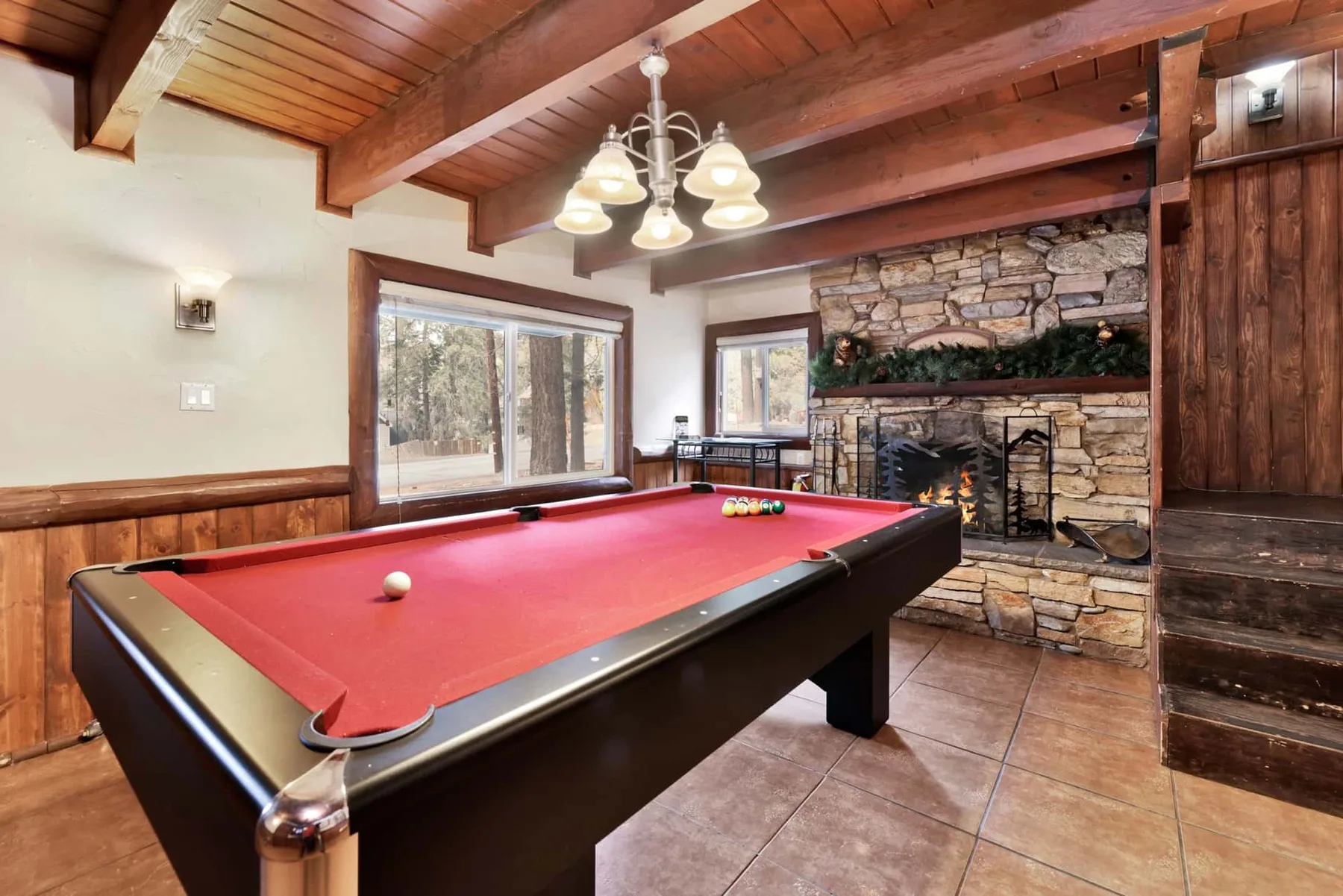 A game room with a pool table and stone fireplace.
