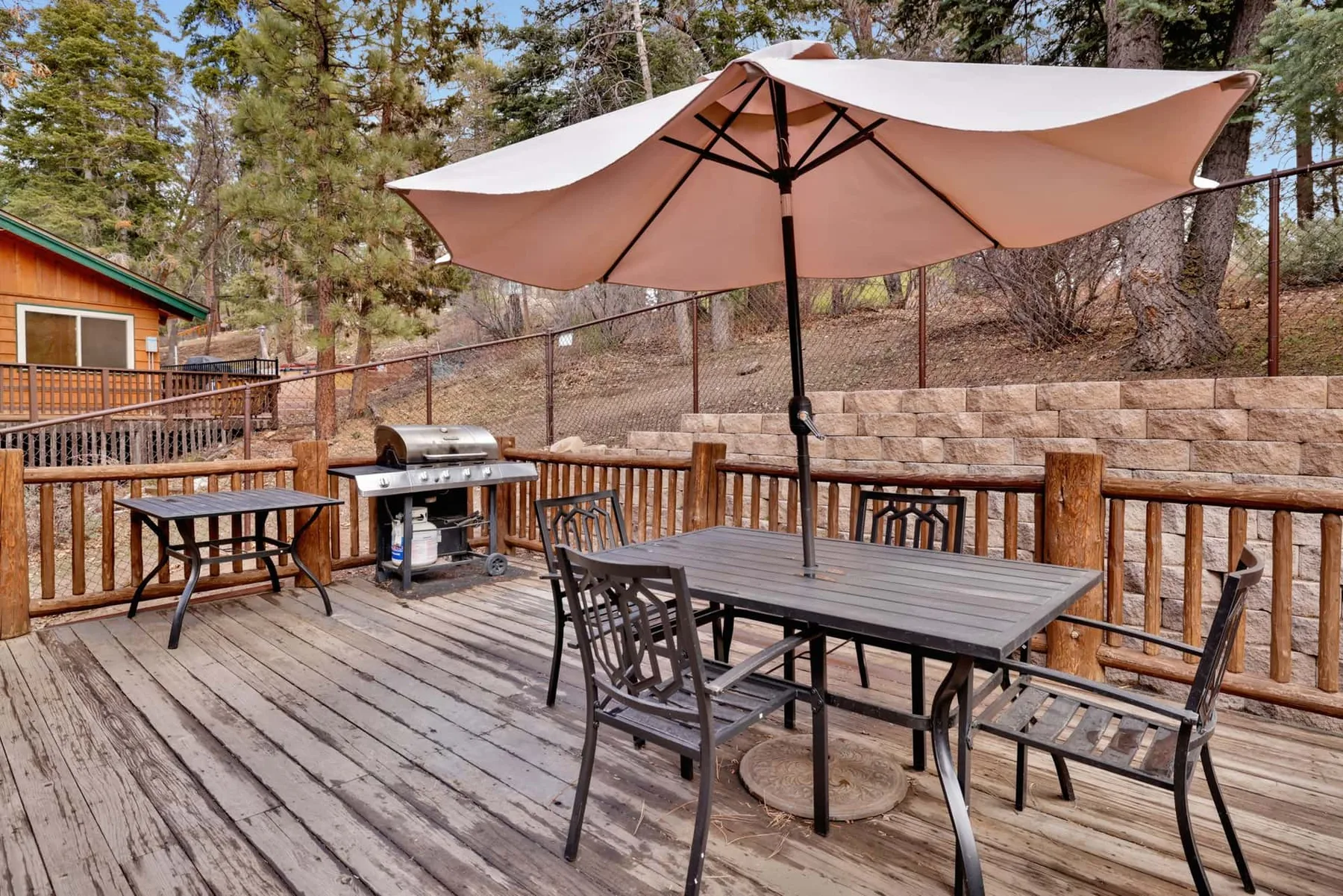 A wooden deck has outdoor seating and a large umbrella.