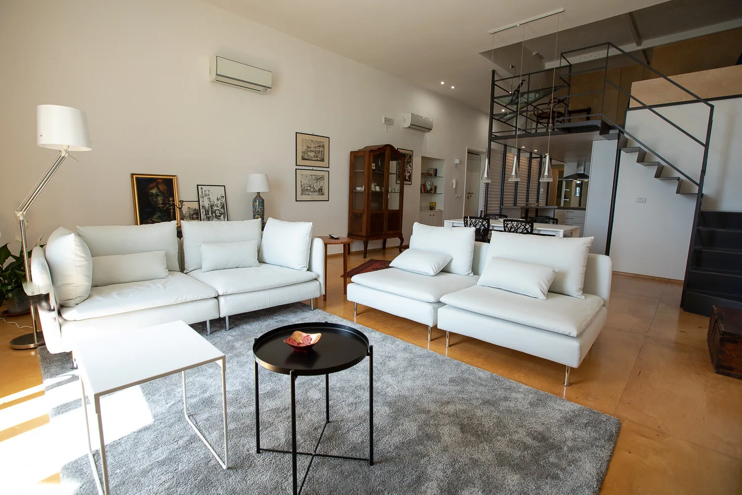 A bright living room with white seating arranged around a coffee table.