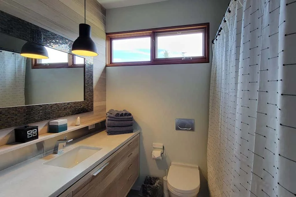 A bathroom with a vanity, toilet, and shower curtain.