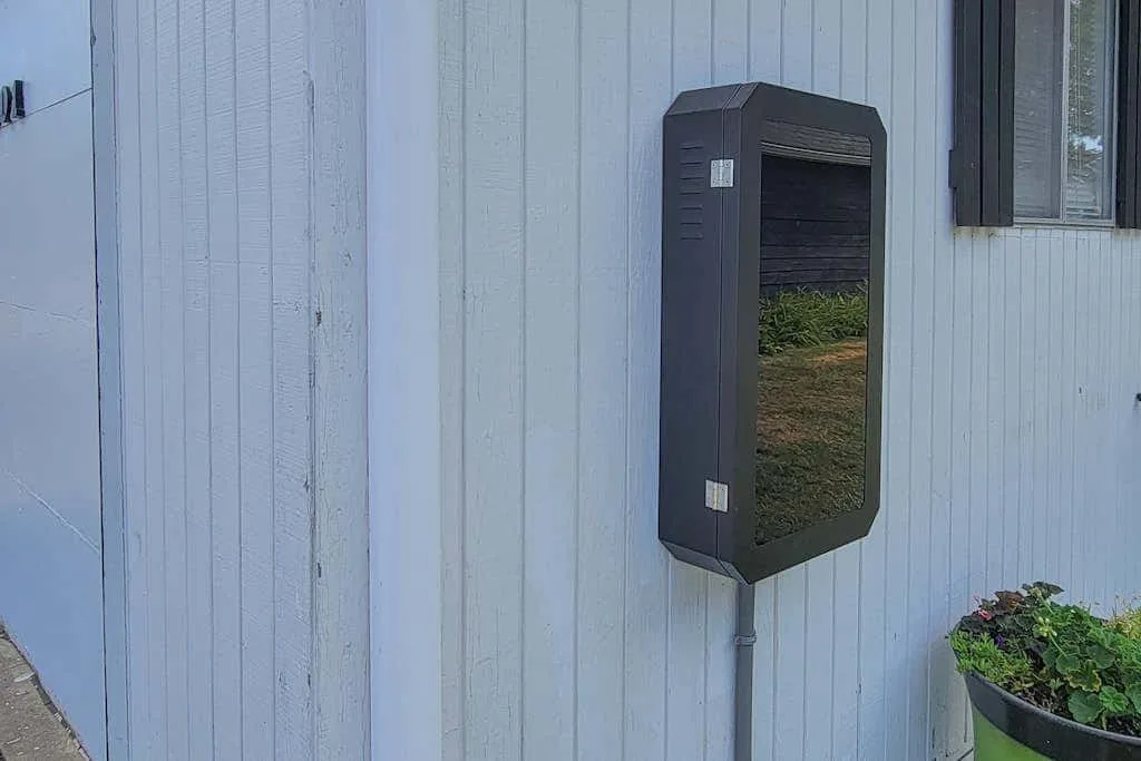 A dark utility box is mounted on the exterior wall beside a window.