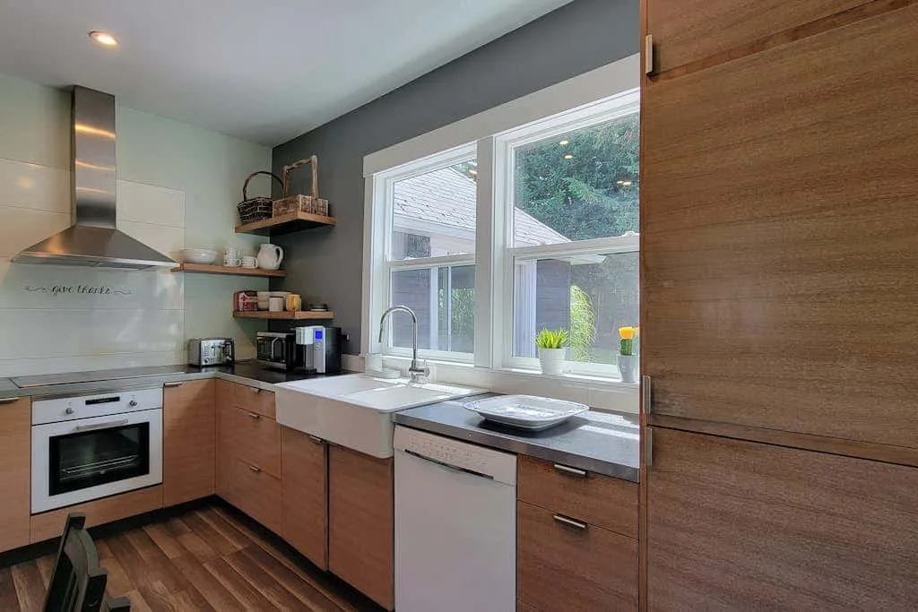 A modern kitchen with wood cabinets, a countertop, and a window above the sink.