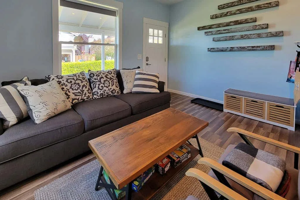 A living room with a sectional sofa, wooden coffee table, and window.