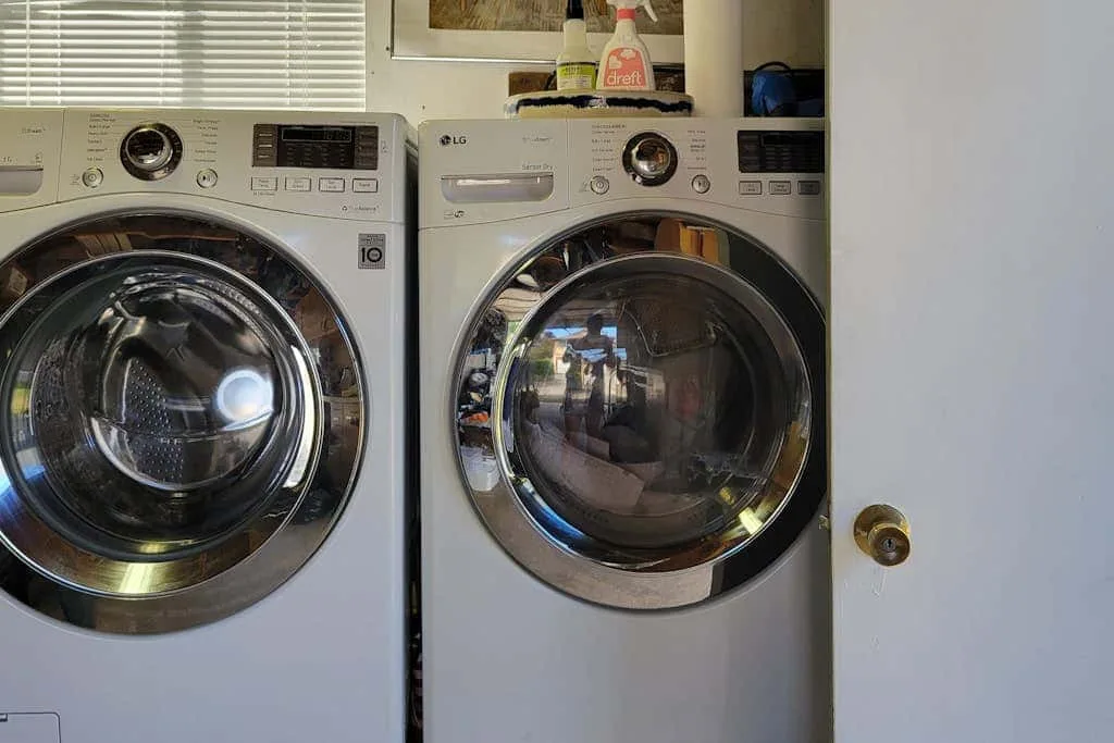 A laundry area with two front-loading machines beneath a window.