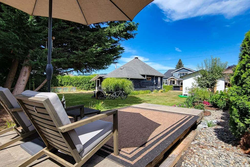 A sunny outdoor patio with cushioned seating, an umbrella, and a low table.