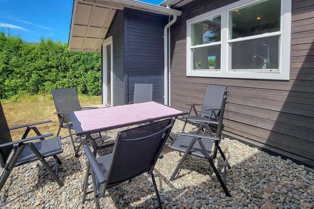 An outdoor dining area with a table and seating beside a house.