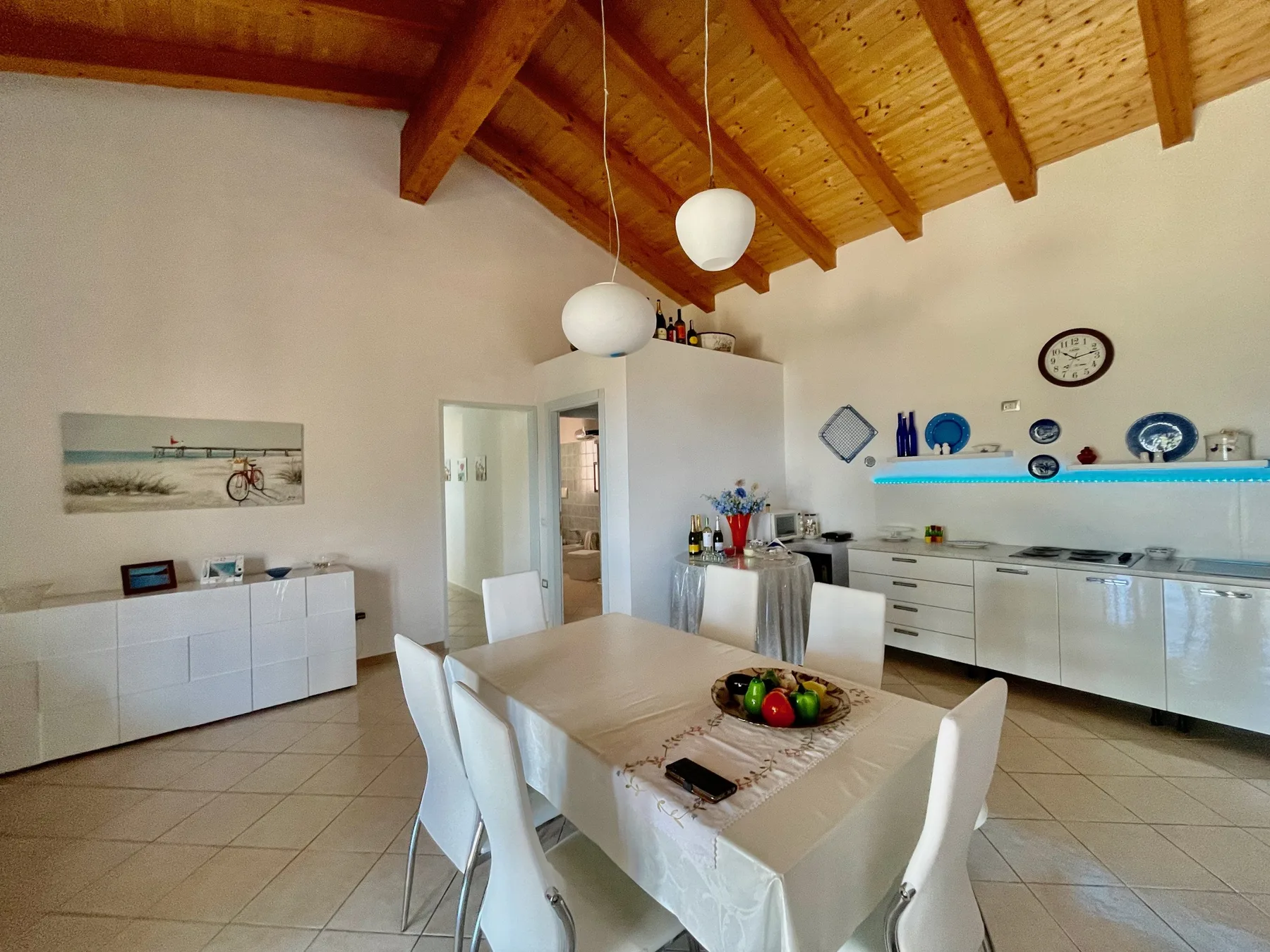 A dining area with a table and chairs beneath a wooden ceiling.