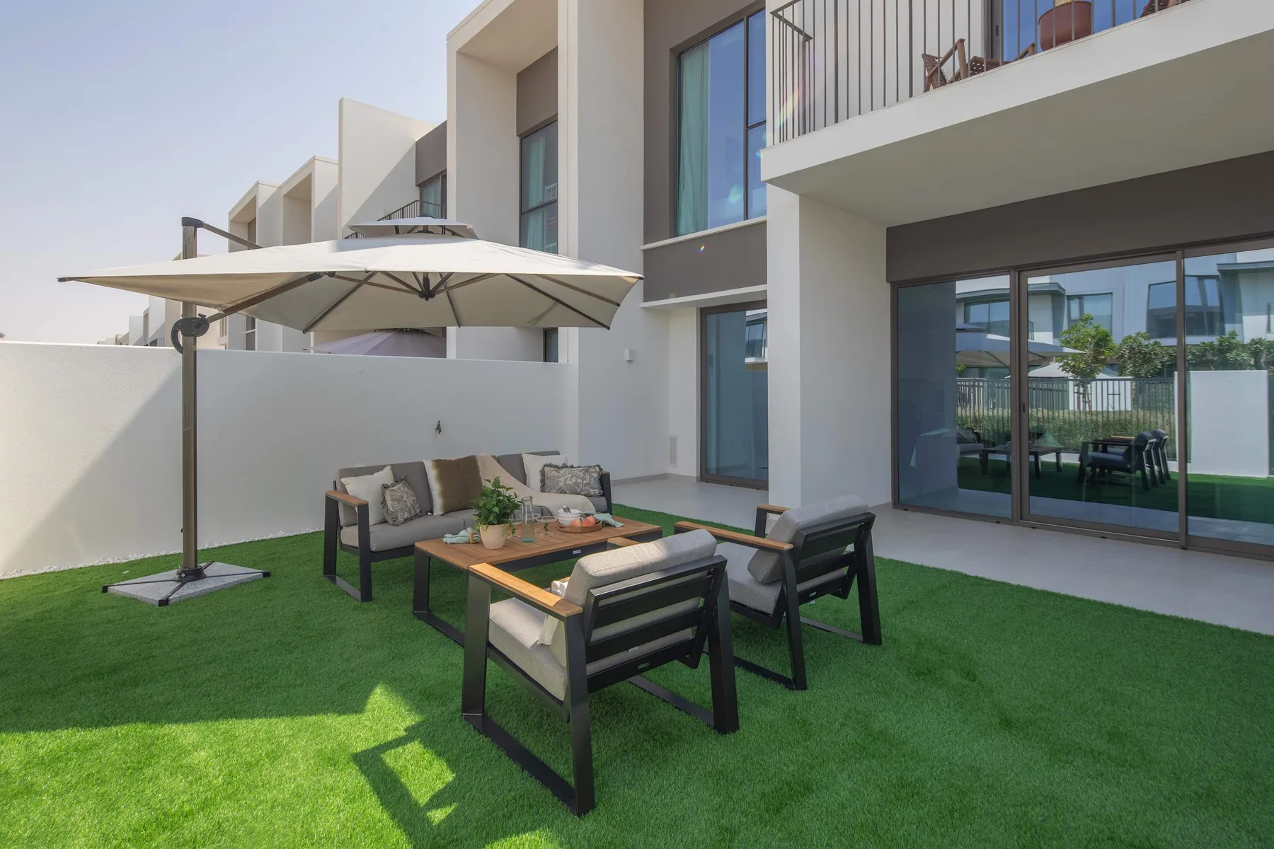Un patio exterior con asientos bajo una gran sombrilla.