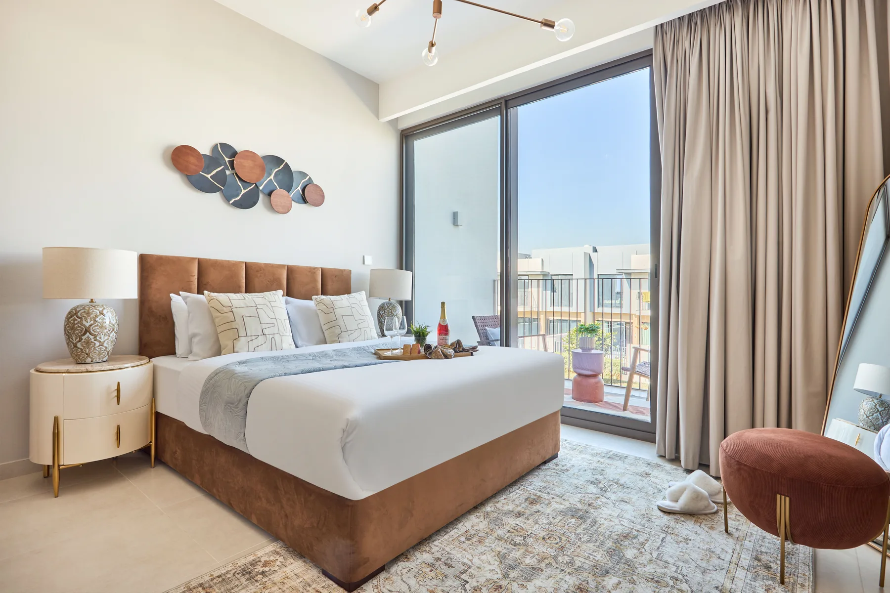 A bright bedroom with a neatly made bed and a large glass balcony door.