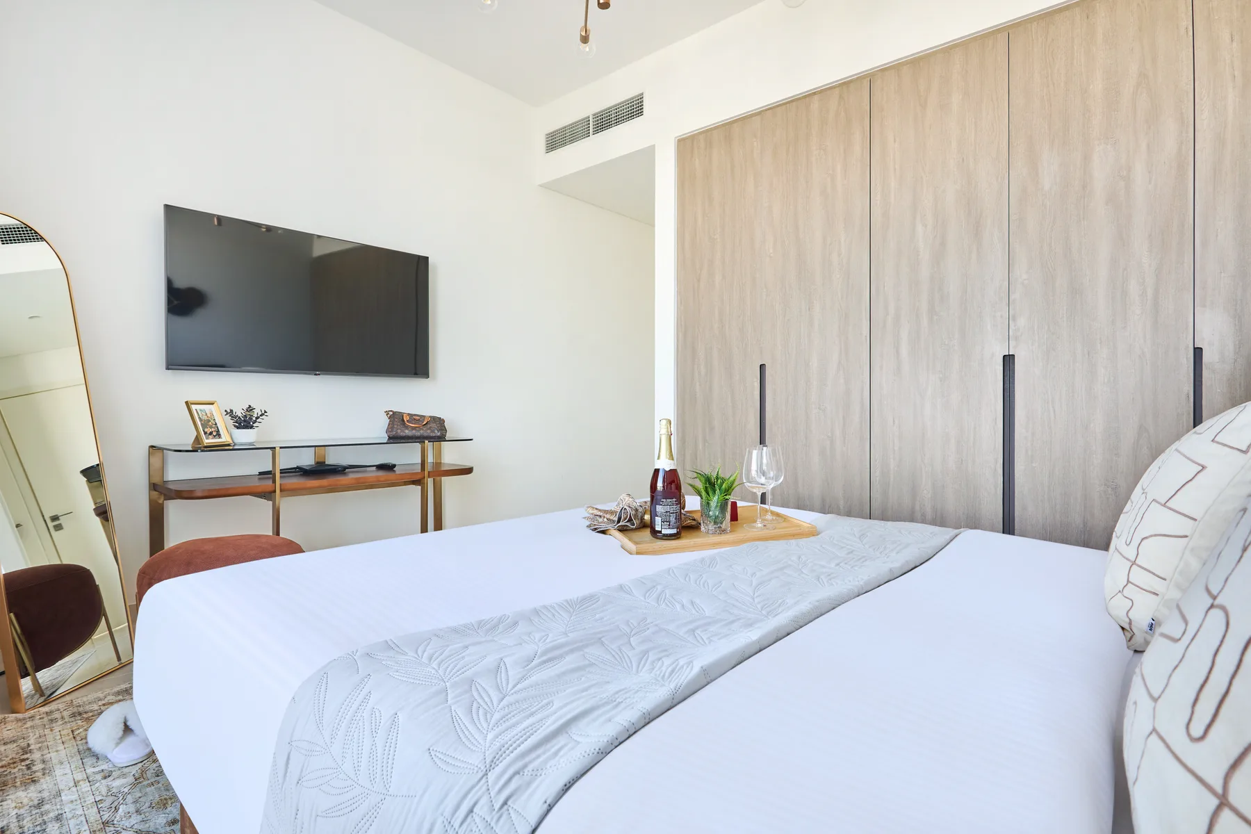 A bedroom with a neatly made bed and a wall-mounted television.
