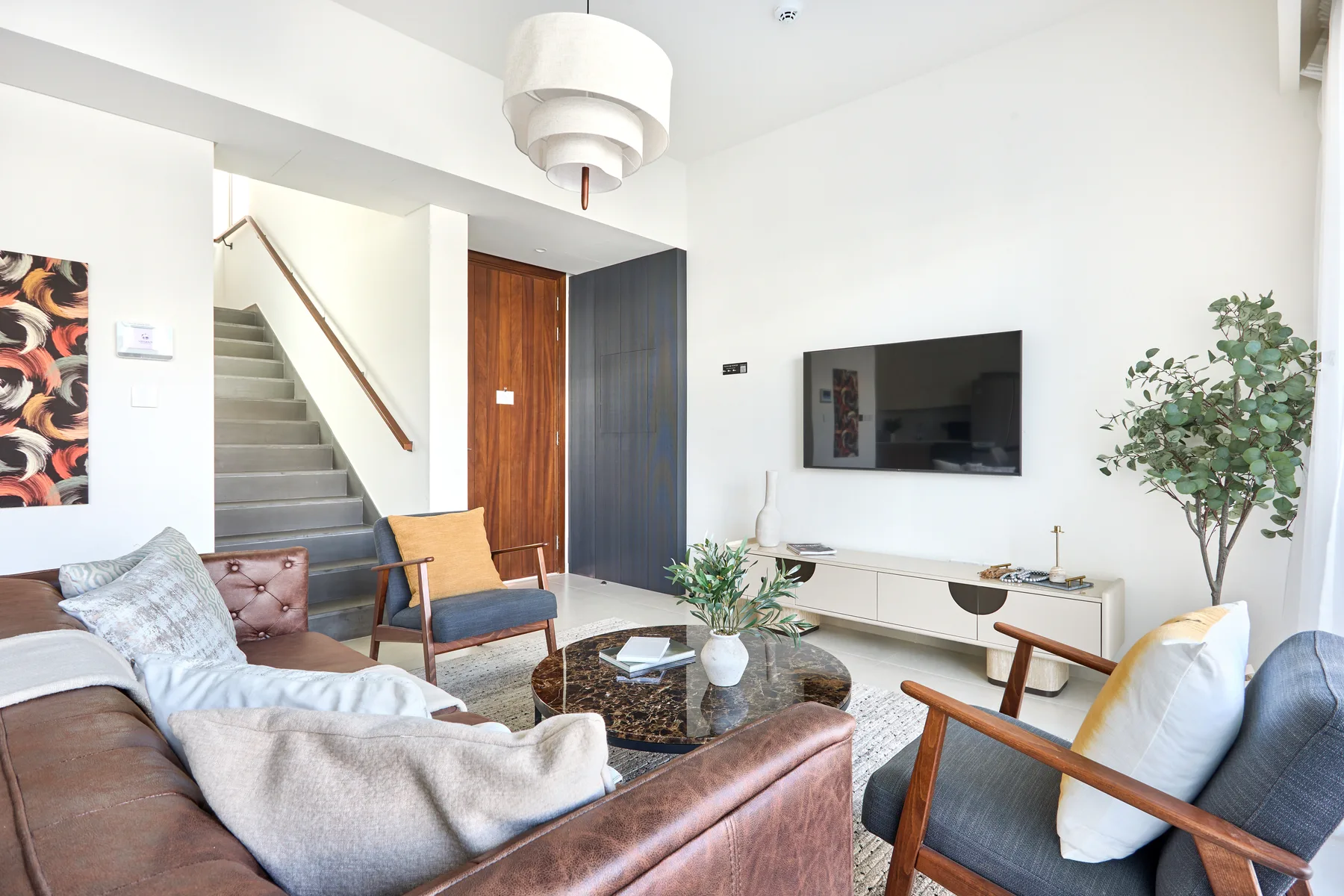 Una sala de estar luminosa con asientos, una mesa de centro y un televisor en la pared.