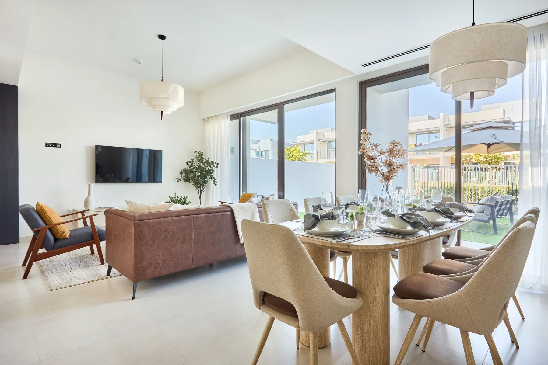 A bright living and dining area with a table beside large windows.