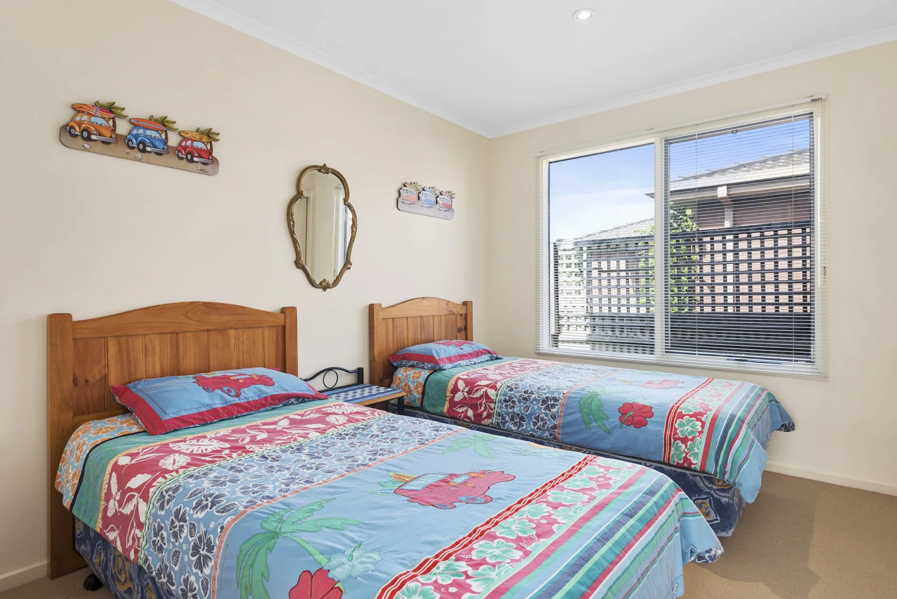 A bedroom with two beds covered in colorful patterned bedding.