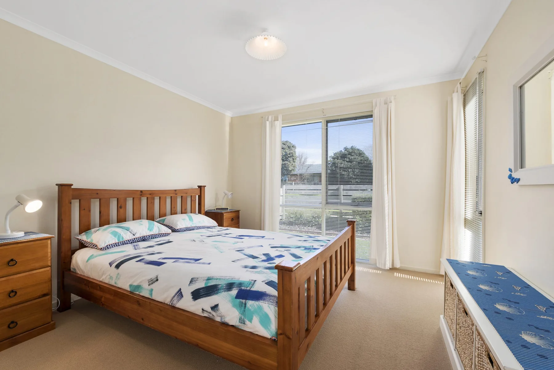 A bedroom with a bed and a window overlooking a garden.