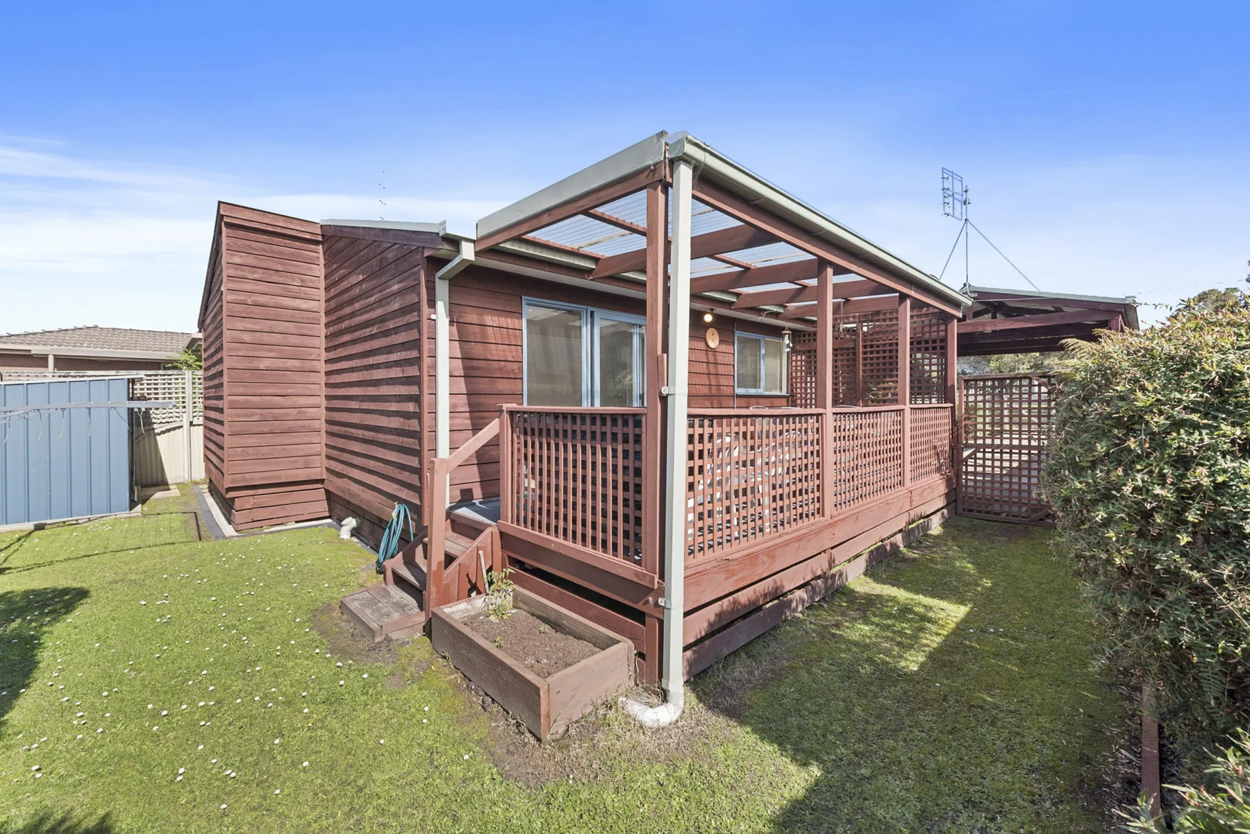 A wooden house with a covered deck and fenced yard.