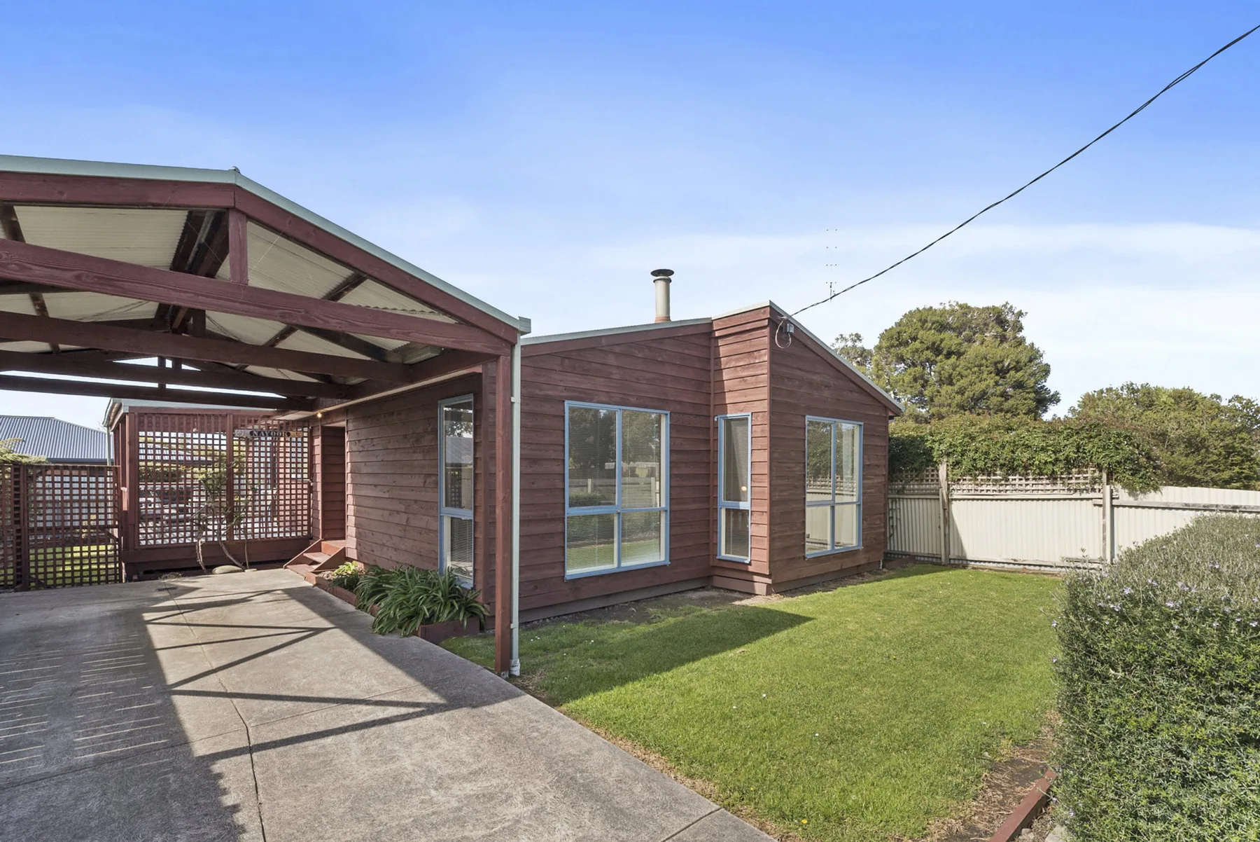A single-story house with a covered carport beside a lawn.