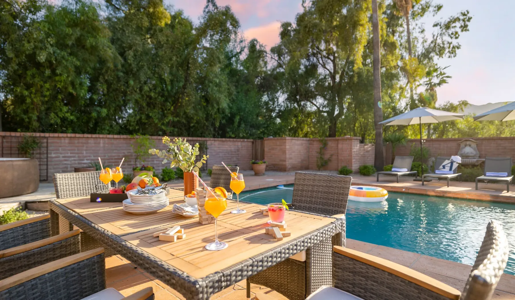 El comedor al aire libre y unas bebidas dan a una piscina y un patio.