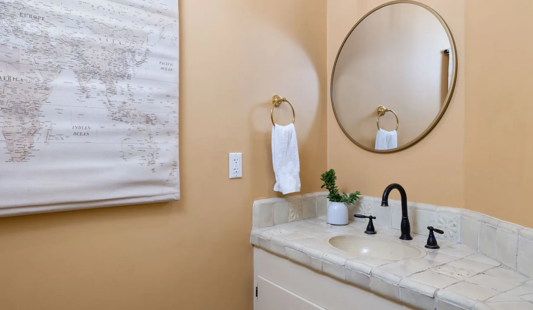 Lavabo de baño con un grifo curvo y un espejo redondo en la pared.