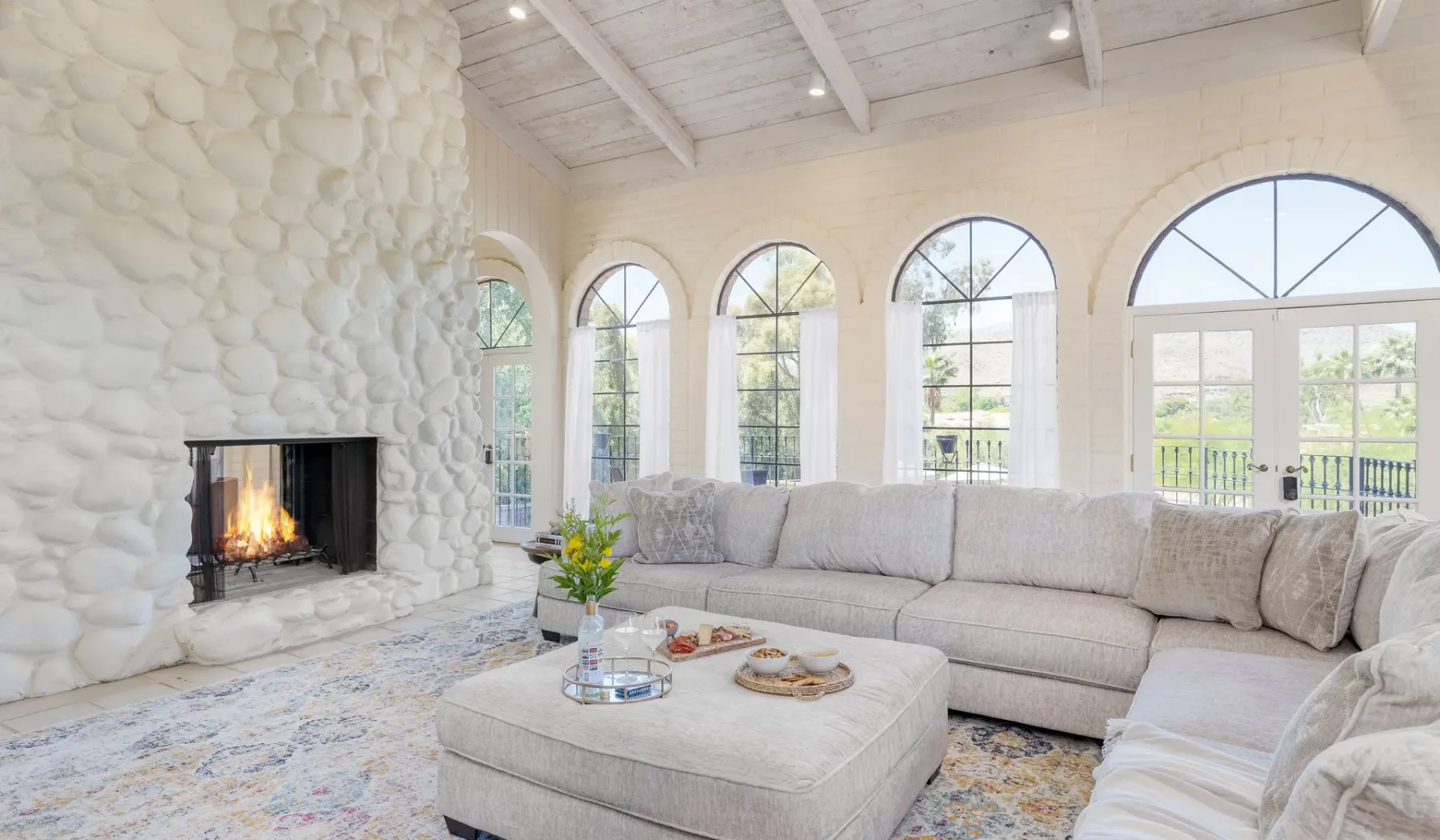 Una sala luminosa con asientos, una chimenea y altas ventanas arqueadas.