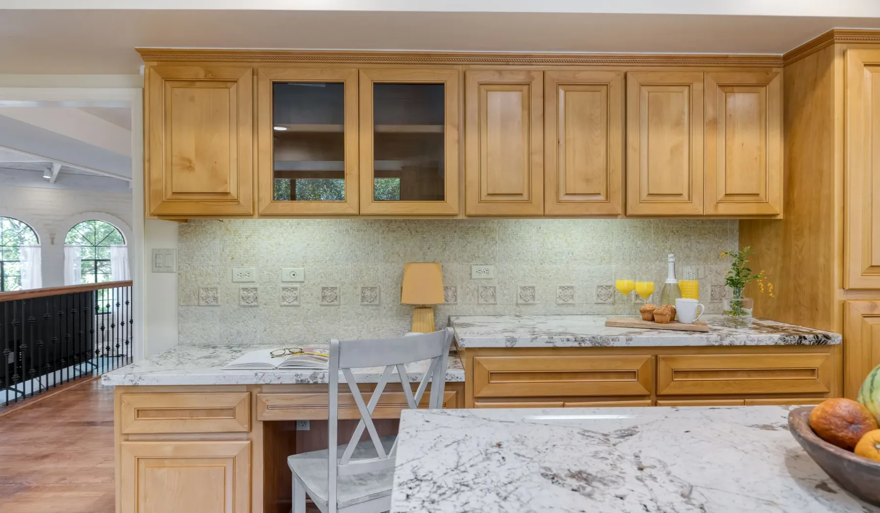 Una cocina con gabinetes de madera, una encimera de mármol y una silla.