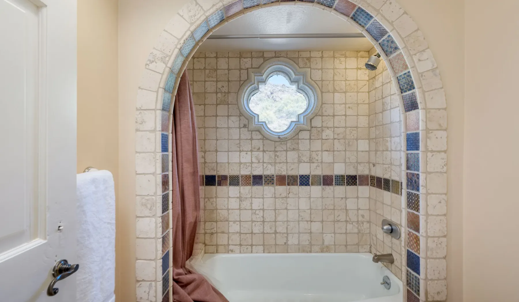 Un baño alicatado con bañera y una abertura arqueada.