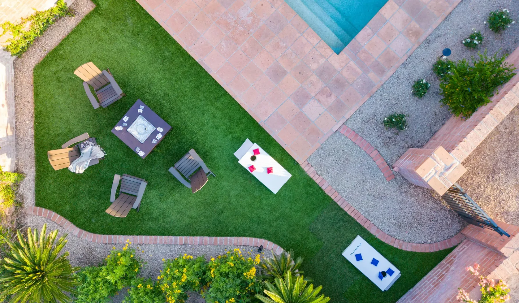 Vista aérea de un patio ajardinado junto a una piscina, con asientos sobre el césped.