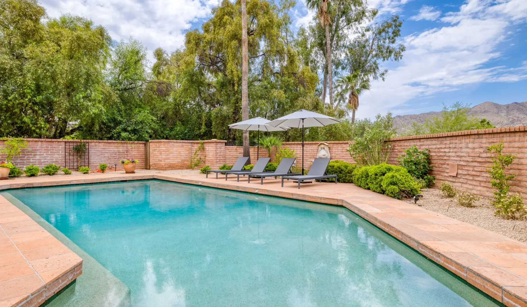 Una piscina al aire libre rodeada de asientos de patio y vegetación.