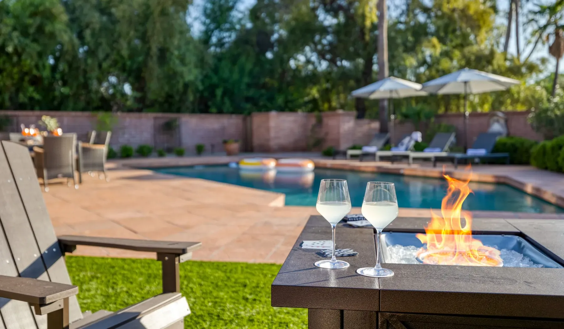 Una piscina y zona de asientos al aire libre con una mesa de fuego.