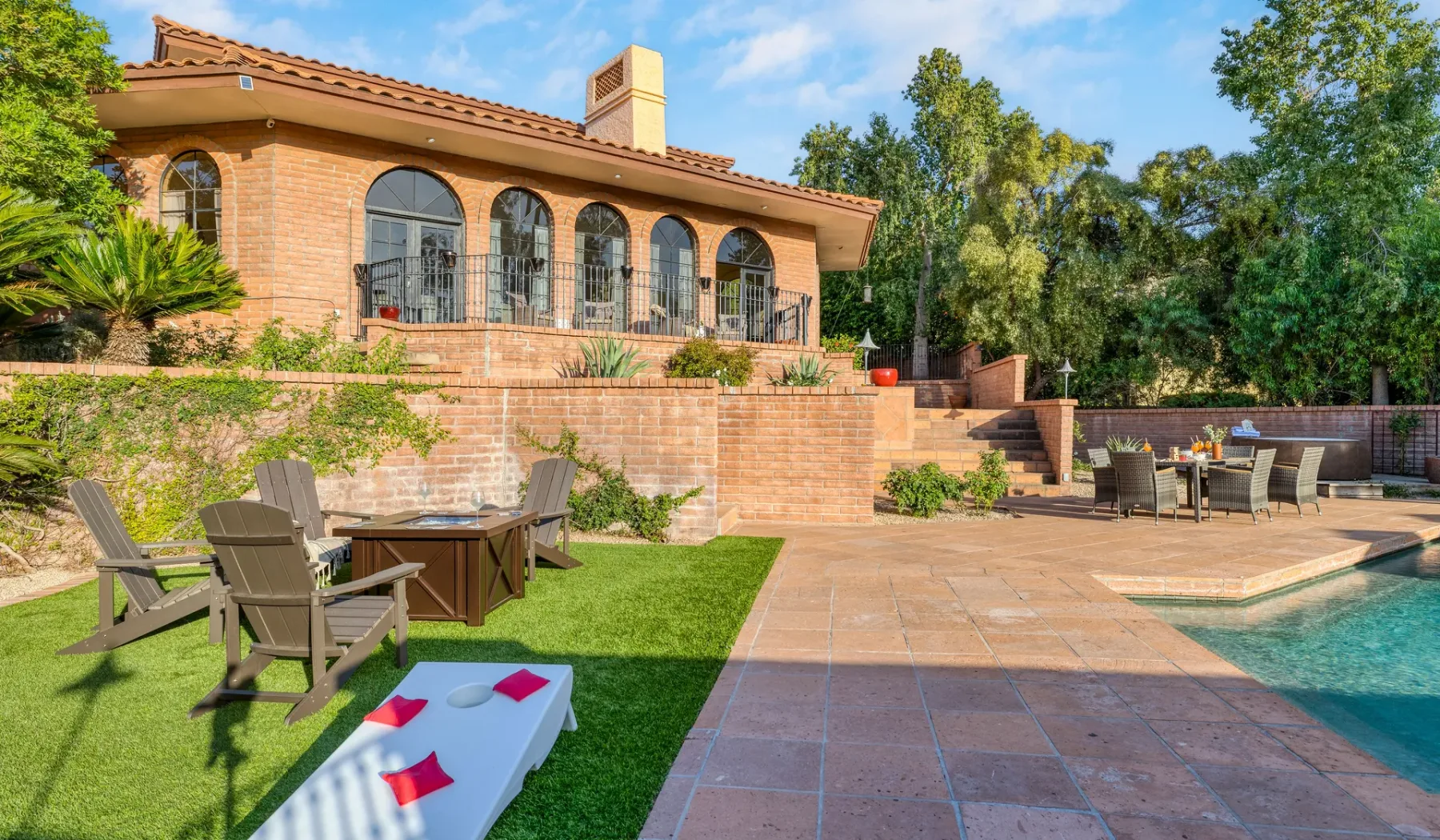 Una casa de ladrillo da a un patio, una piscina y una zona de estar al aire libre.