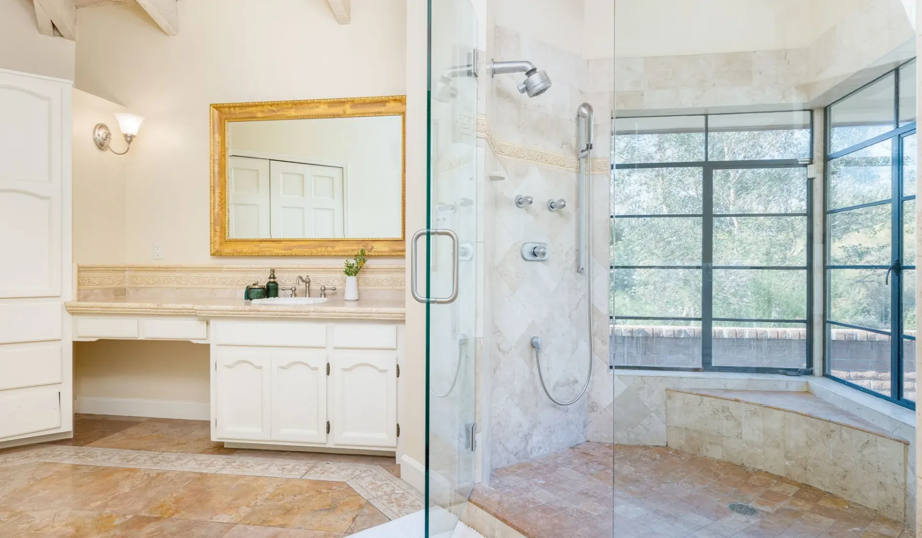 Un baño luminoso con ducha de vidrio y ventanales.