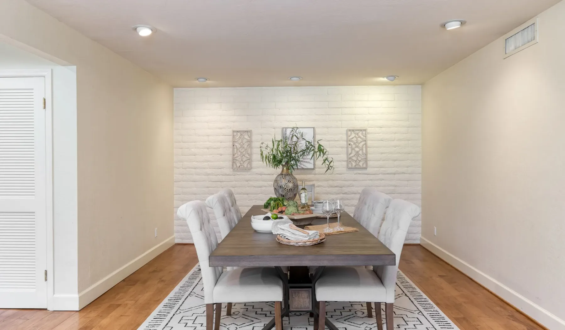 Un comedor con una mesa de madera, asientos tapizados y una pared decorativa.
