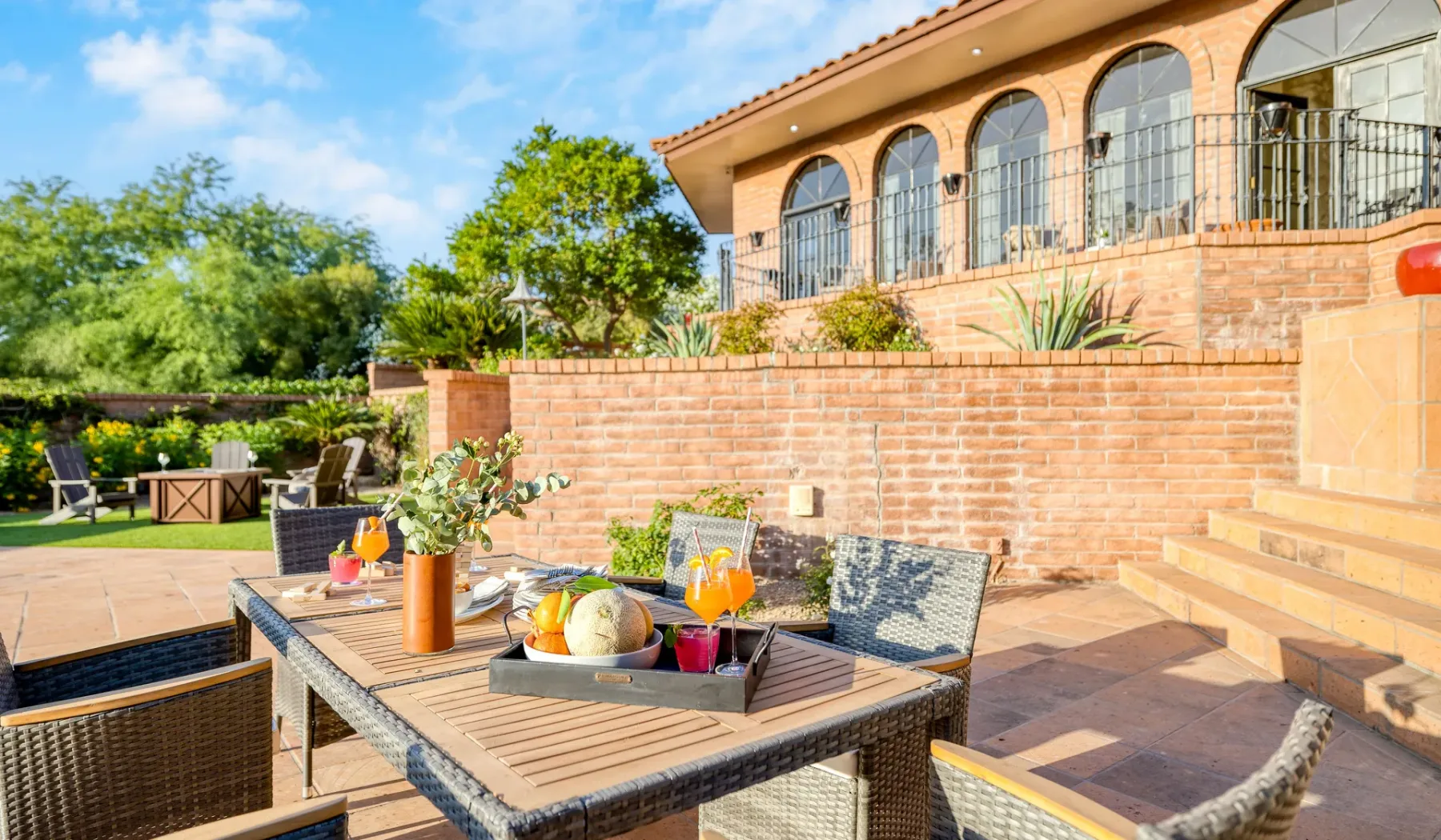 Comedor al aire libre en un patio, con una mesa junto a un muro de ladrillo.