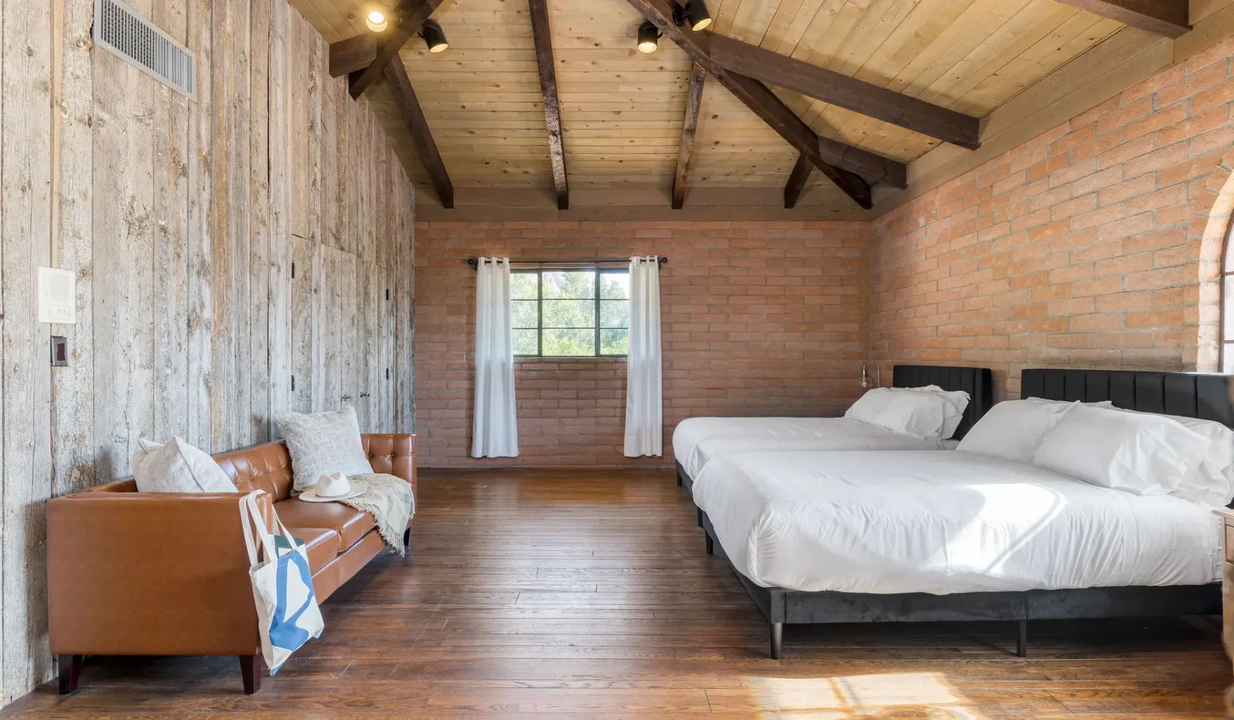 Un dormitorio con una cama grande, una ventana y una pequeña zona de estar.